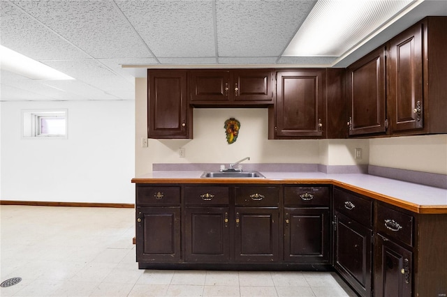 kitchen featuring dark brown cabinets, sink, and a paneled ceiling