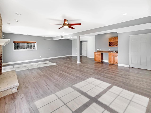 unfurnished living room with ceiling fan, light hardwood / wood-style flooring, and sink