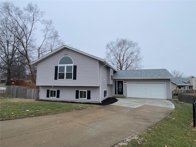 tri-level home with a garage, fence, concrete driveway, and a front yard