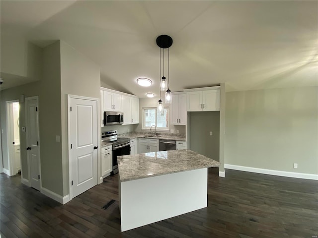 kitchen featuring white cabinetry, vaulted ceiling, appliances with stainless steel finishes, a center island, and decorative light fixtures