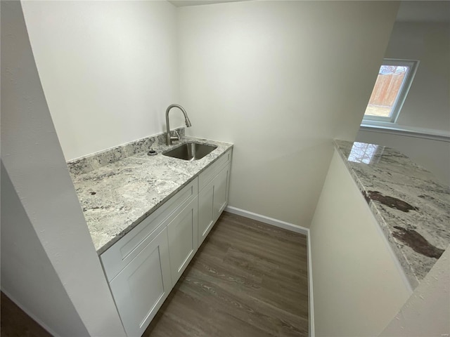 interior space with dark wood-style flooring, a sink, and baseboards