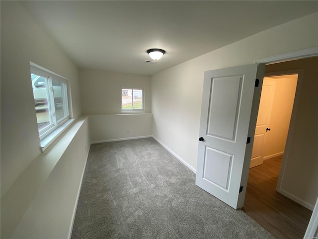 empty room with dark colored carpet and baseboards