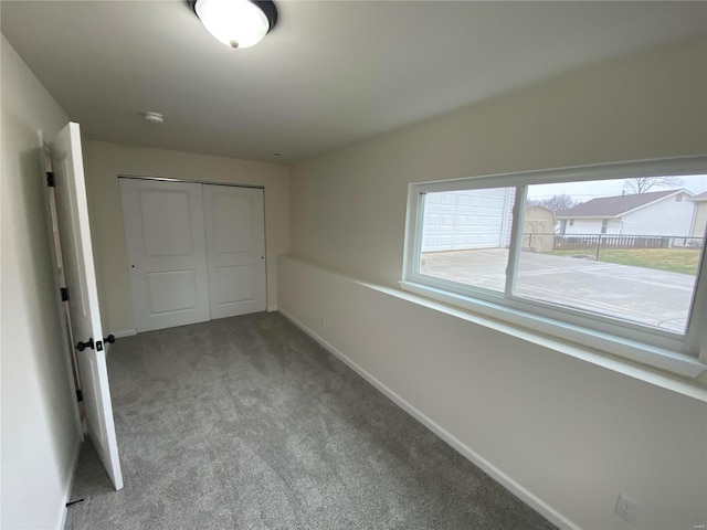 unfurnished bedroom with baseboards, a closet, and light colored carpet