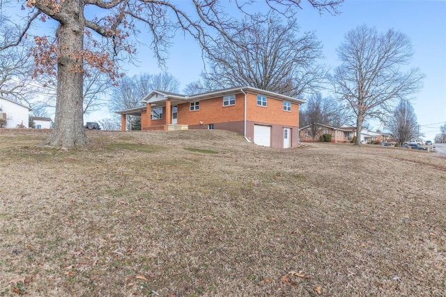 exterior space featuring a garage, a yard, and brick siding