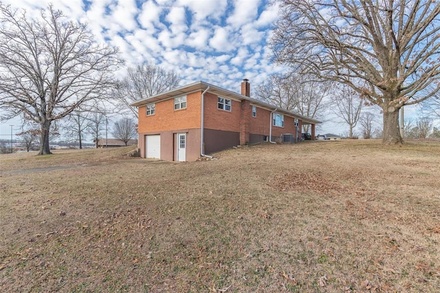 view of side of home featuring a garage, brick siding, a chimney, and a lawn