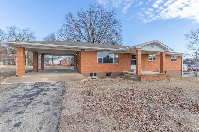 single story home featuring driveway, a carport, and brick siding