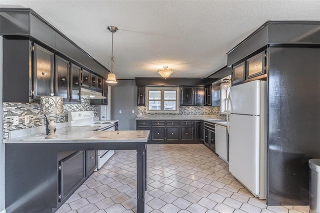 kitchen featuring light countertops, a sink, a peninsula, white appliances, and under cabinet range hood