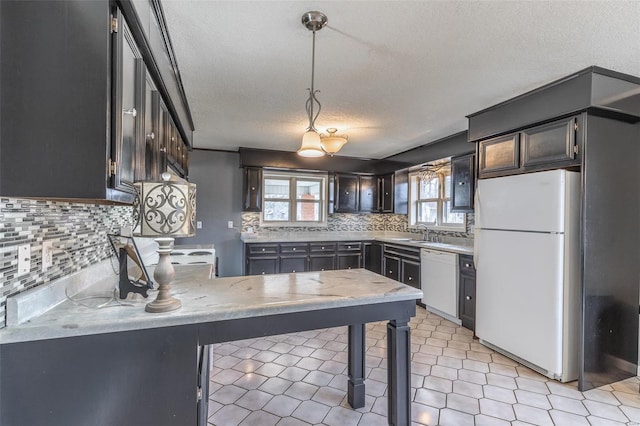 kitchen featuring white appliances, hanging light fixtures, a peninsula, a sink, and backsplash