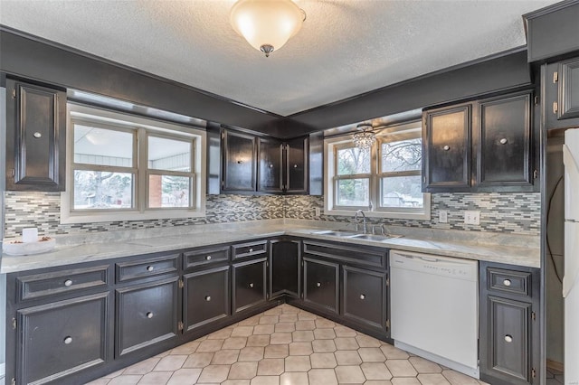 kitchen with light countertops, backsplash, white dishwasher, and a sink