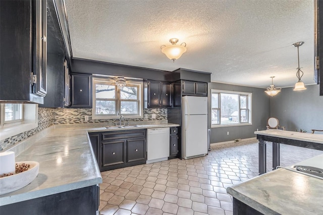 kitchen featuring pendant lighting, light countertops, decorative backsplash, a sink, and white appliances