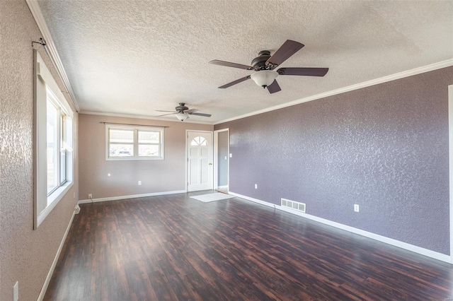 spare room with a textured wall, wood finished floors, visible vents, and crown molding