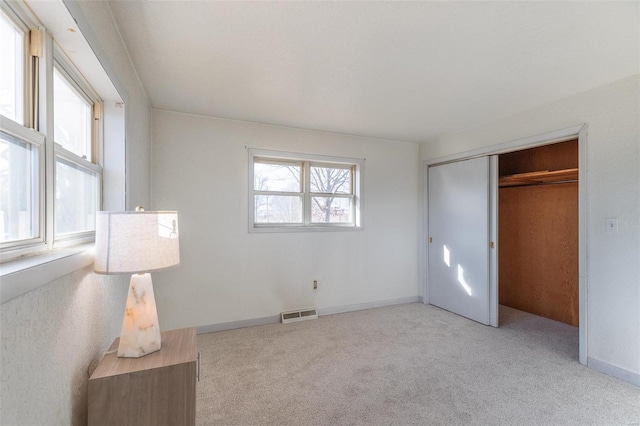 unfurnished bedroom featuring light carpet, baseboards, visible vents, and a closet