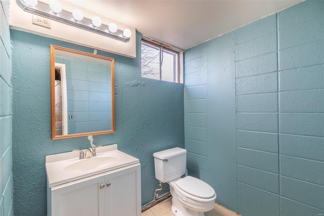 half bath with a textured wall, vanity, and toilet