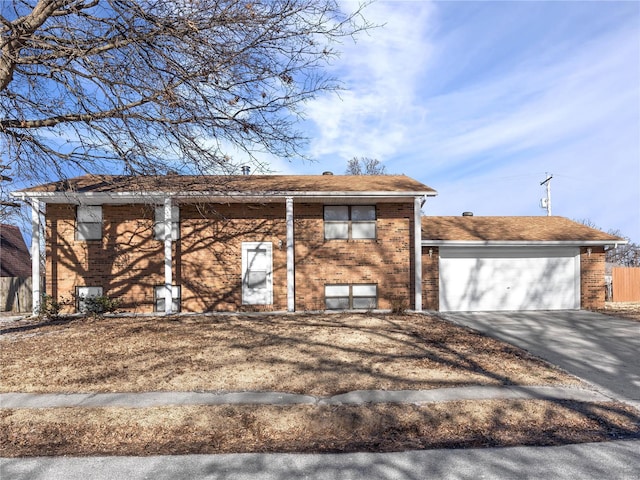 raised ranch with driveway, a garage, and brick siding