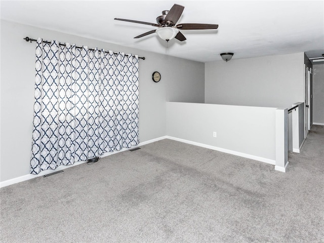 carpeted empty room featuring a ceiling fan, visible vents, and baseboards