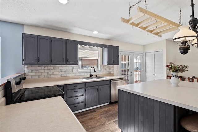 kitchen with dark wood-style flooring, tasteful backsplash, light countertops, appliances with stainless steel finishes, and a sink