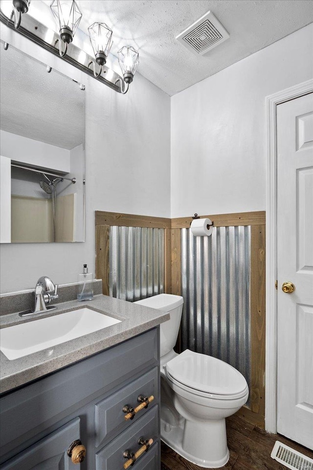 bathroom with visible vents, vanity, a textured ceiling, and wood finished floors