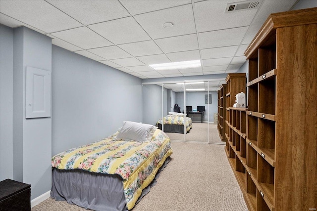 bedroom with baseboards, visible vents, a drop ceiling, and light colored carpet