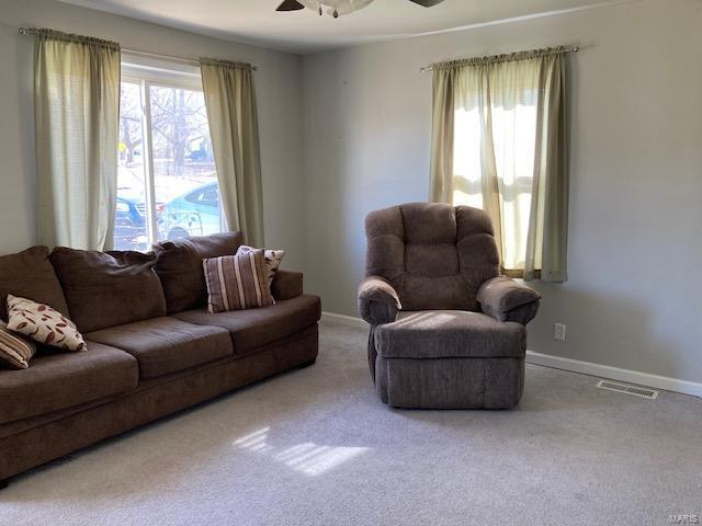 carpeted living area with baseboards, a ceiling fan, and a wealth of natural light