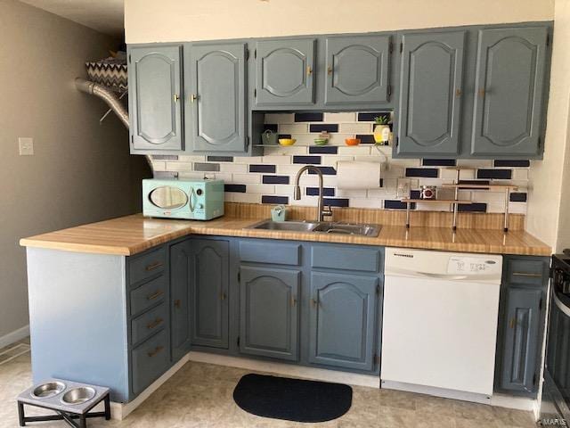 kitchen with light countertops, white appliances, backsplash, and a sink