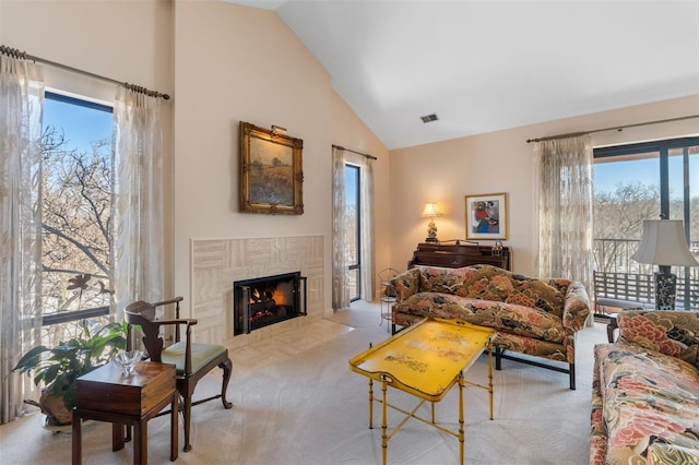 carpeted living area featuring visible vents, high vaulted ceiling, and a premium fireplace