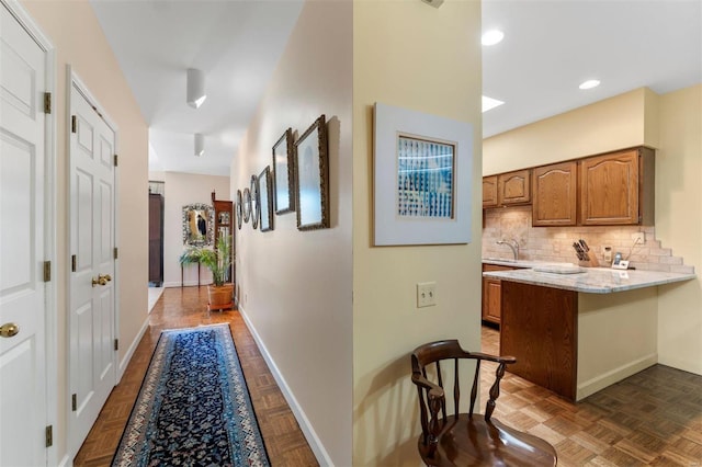 hallway with recessed lighting, baseboards, and a sink