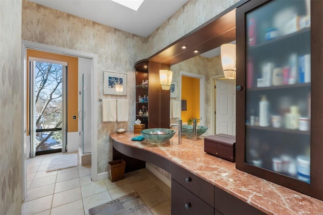 bathroom with tile patterned floors, a shower stall, wallpapered walls, baseboards, and vanity