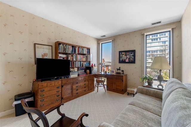 carpeted office space featuring wallpapered walls, baseboards, and visible vents