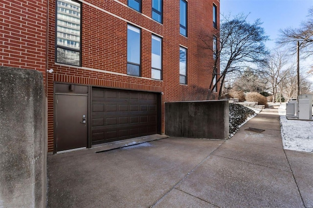 view of side of property with brick siding, driveway, and an attached garage