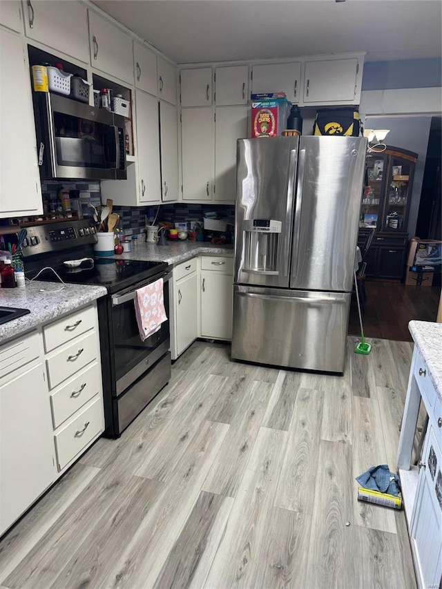 kitchen featuring light hardwood / wood-style floors, white cabinetry, stainless steel appliances, and tasteful backsplash