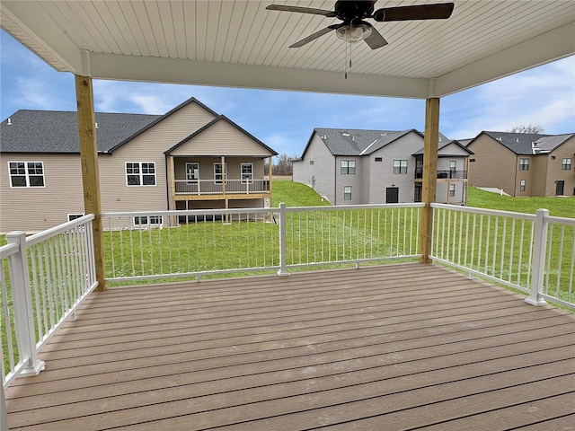 wooden deck featuring a yard, a residential view, and a ceiling fan