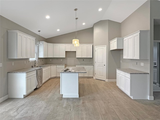 kitchen with decorative light fixtures, a kitchen island, stainless steel dishwasher, light stone counters, and white cabinets