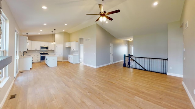 kitchen featuring appliances with stainless steel finishes, light hardwood / wood-style flooring, pendant lighting, a kitchen island, and white cabinetry