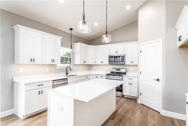 kitchen with a kitchen island, sink, stainless steel appliances, and white cabinetry