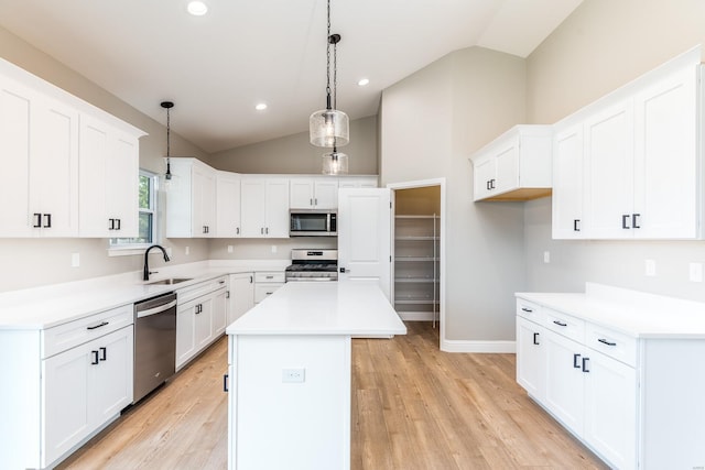 kitchen with appliances with stainless steel finishes, hanging light fixtures, a center island, sink, and white cabinetry