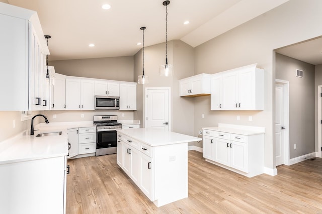 kitchen featuring white cabinets, stainless steel appliances, a kitchen island, and sink