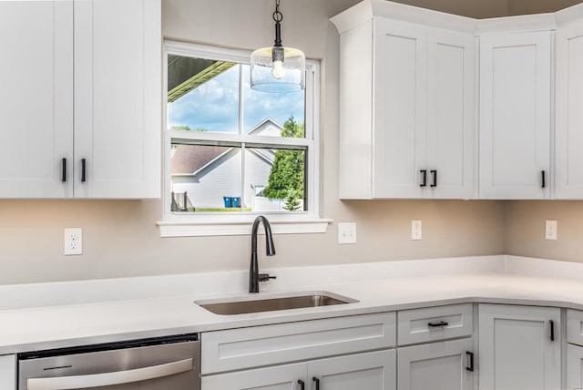 kitchen featuring stainless steel dishwasher, sink, white cabinetry, and hanging light fixtures