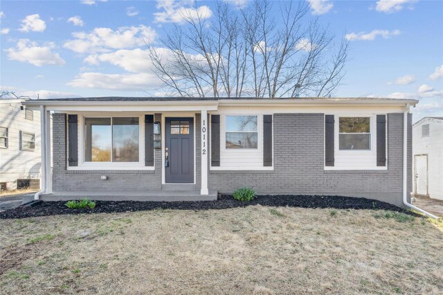 view of front of house featuring brick siding, a front lawn, and a porch