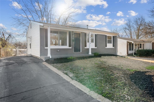 view of front of house featuring aphalt driveway, a front yard, brick siding, and fence