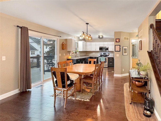 dining area with sink, a chandelier, and dark hardwood / wood-style floors