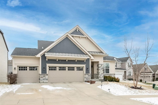 view of front of home with metal roof, an attached garage, driveway, board and batten siding, and a standing seam roof