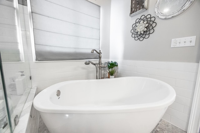 bathroom with a tub and tile walls