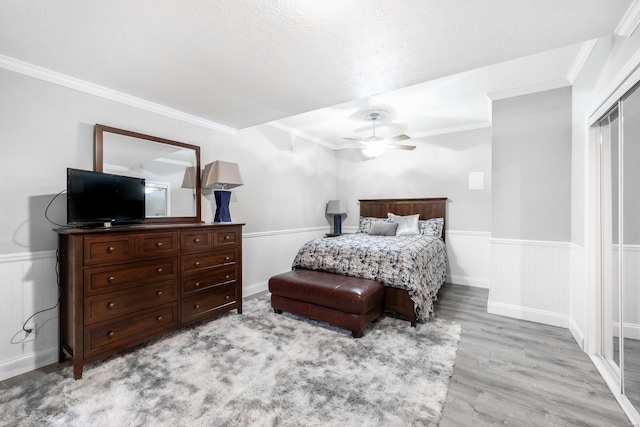 bedroom with light wood-type flooring, crown molding, and ceiling fan