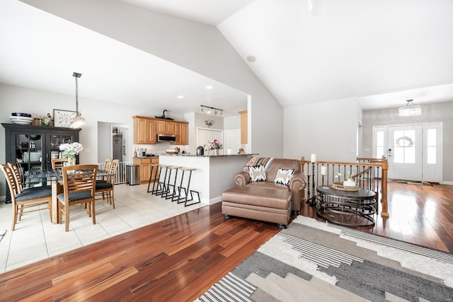 living room featuring high vaulted ceiling, a notable chandelier, and light hardwood / wood-style flooring