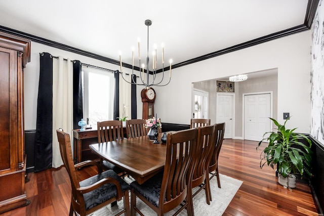 dining area with a chandelier, dark wood-type flooring, and ornamental molding