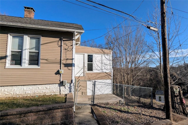 view of home's exterior with a chimney, fence, and a gate