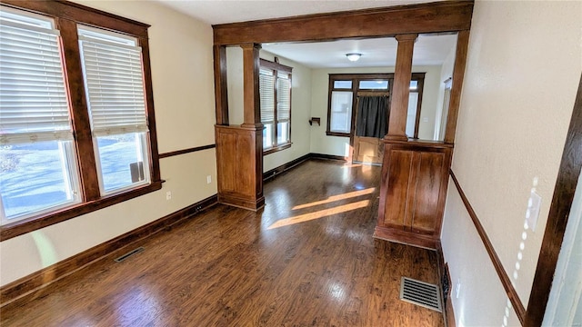 foyer entrance featuring dark wood-style floors, decorative columns, visible vents, and baseboards