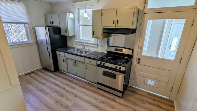 kitchen with dark countertops, visible vents, appliances with stainless steel finishes, a sink, and under cabinet range hood