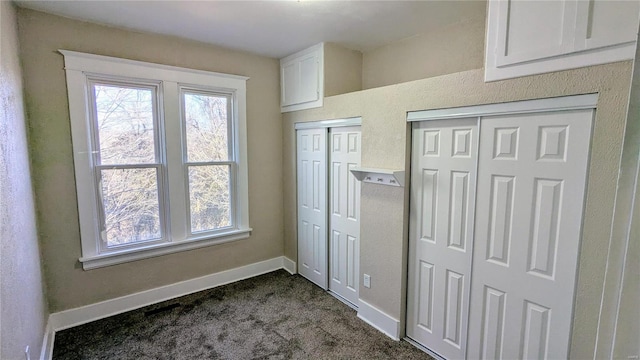 unfurnished bedroom with carpet floors, multiple windows, baseboards, and multiple closets