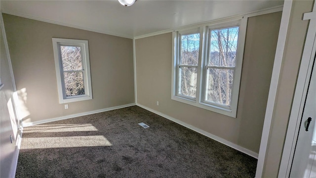 spare room featuring ornamental molding, dark colored carpet, visible vents, and baseboards